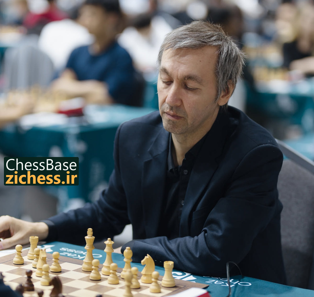گاتا کامسکی پشت صفحهٔ شطرنج در آتیراو؛ عکس: فدراسیون شطرنج قزاقستان؛ منبع: ChessBase.